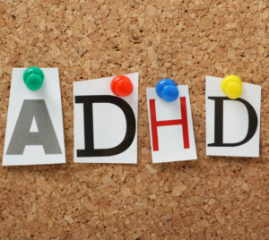 Initials ADHD thumbtacked to a corkboard